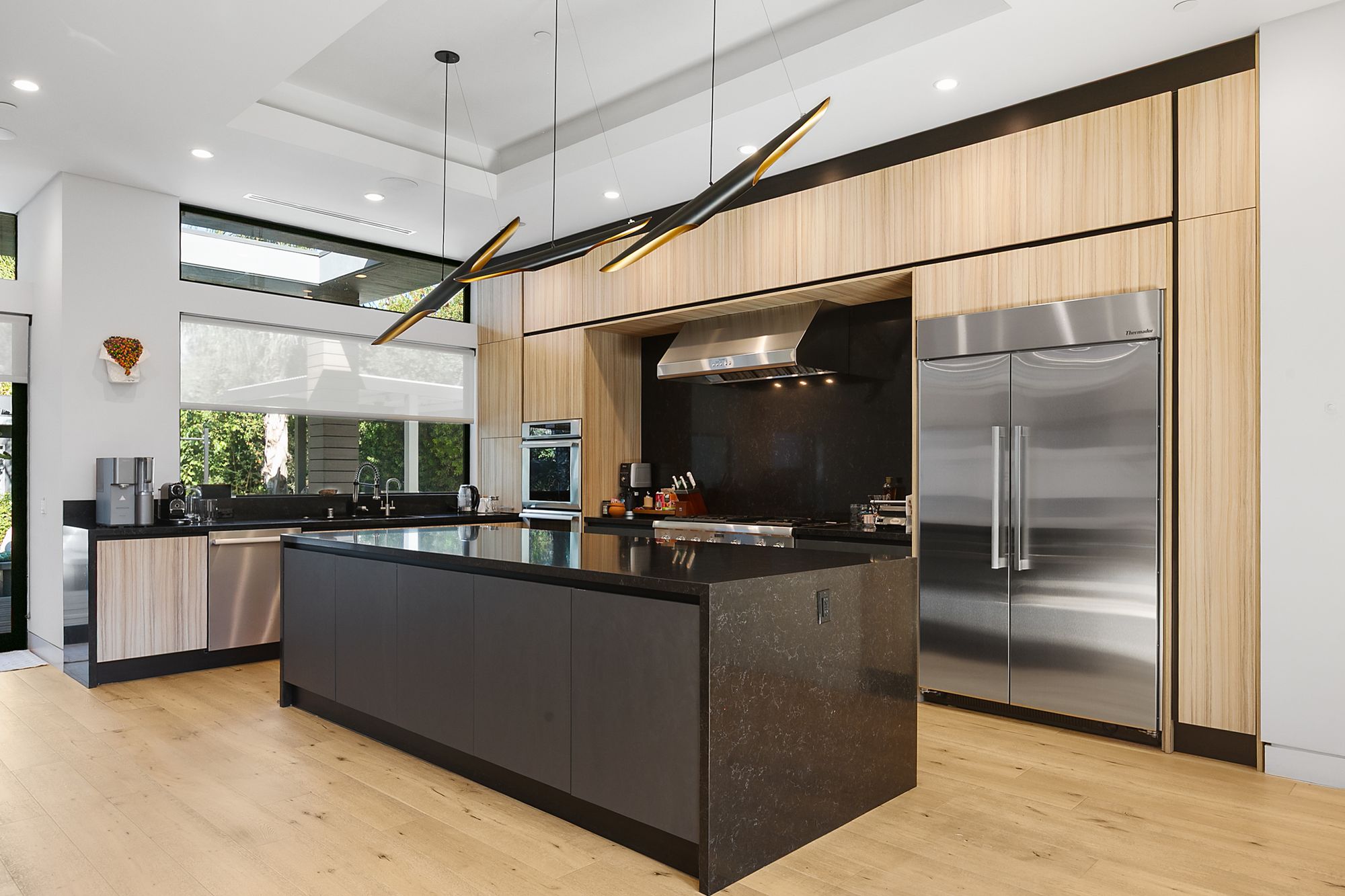 Remodeled kitchen with a dark island, light wood cabinetry, and a black quartz countertop