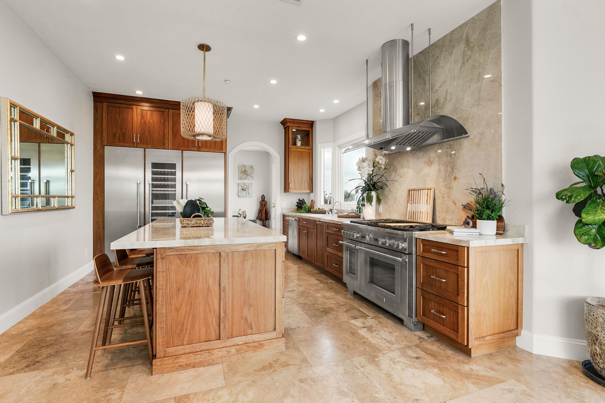 Open kitchen with walnut cabinetry, a marble island, and travertine floors